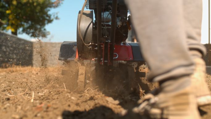 超级SLO-MO园丁使用前齿耕耘机犁过坚硬的泥土和土壤