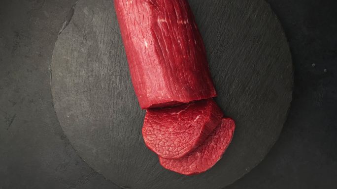 新鲜生牛肉黑色背景上的烤牛肉，旋转360度。俯视图