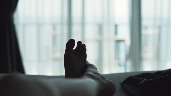 在度假期间，放松的女人躺在床上的毯子上，交叉腿，在酒店度假区看风景