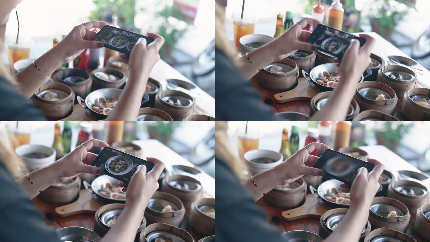 一位亚洲妇女正在用手机拍摄桌子上的食物。