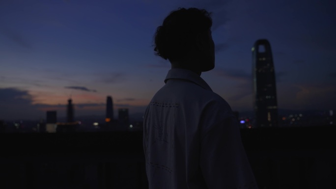 夜晚男生站在天台俯瞰城市