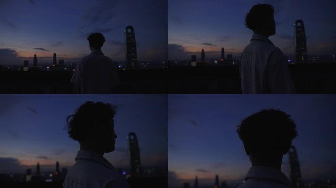 夜晚男生站在天台俯瞰城市