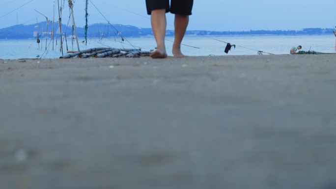 渔民光脚走在沙滩上