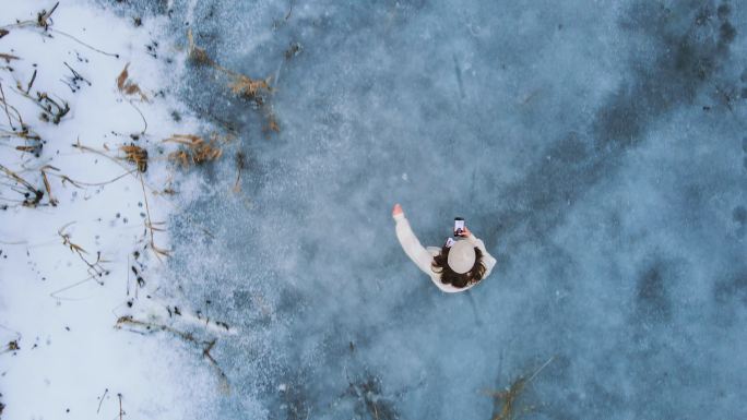 上图：一名女子在冰冻的湖面上滑冰时使用手机的照片