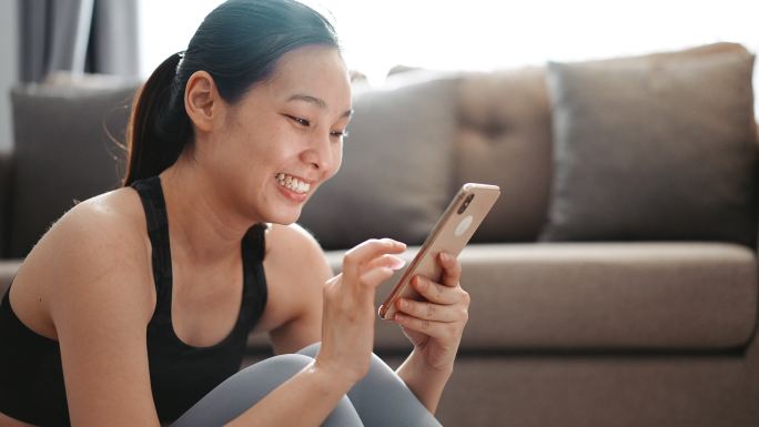 运动妇女在家里使用智能手机