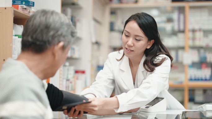 亚裔中国女药剂师在药店药房与一名资深男子一起测量血压