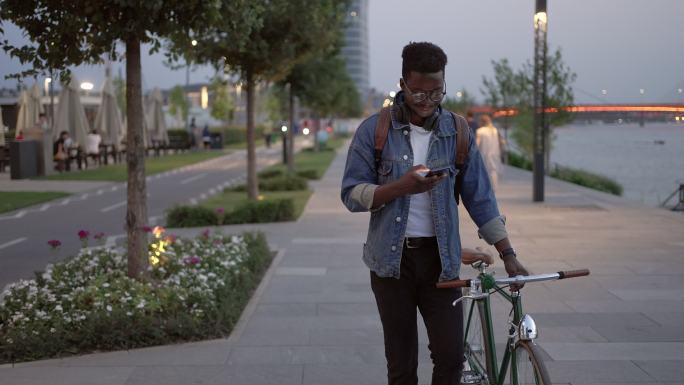 一个年轻人晚上在人行道上骑自行车