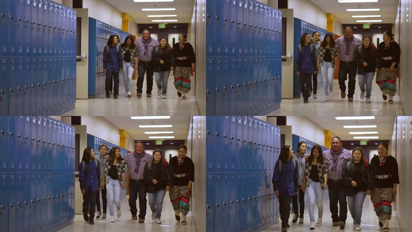 一群中学生和他们的老师一起穿过学校走廊
