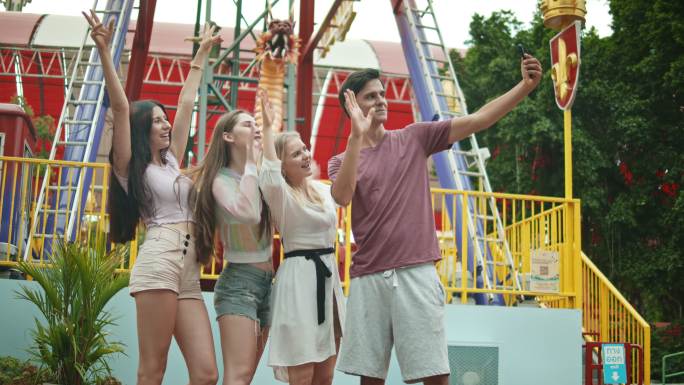 四个人在游乐园通过智能手机自拍的照片