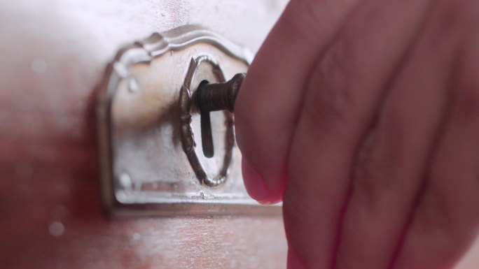 一只手用钥匙打开古代保险箱的特写镜头。