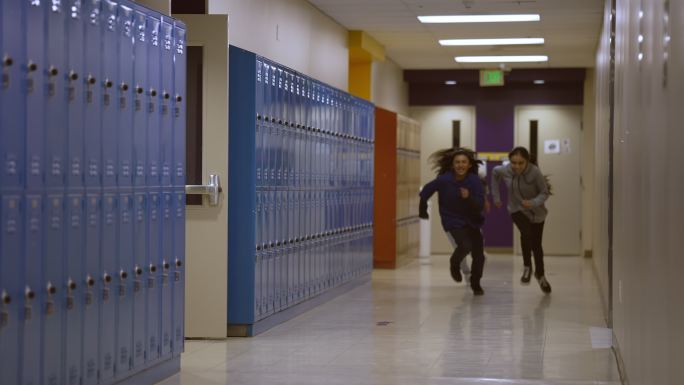 三个中学生和高中生快速穿过学校走廊