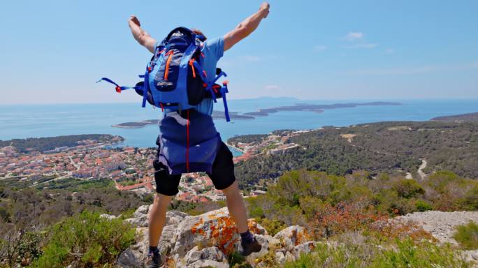 一名背着背包的男子在赫瓦尔岛的山顶上举起双臂跳跃