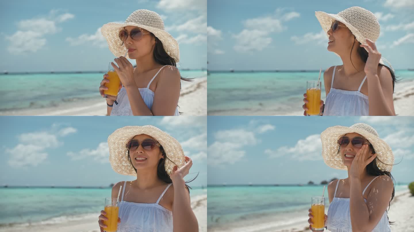 美丽的女人喝橙汁在海滩上