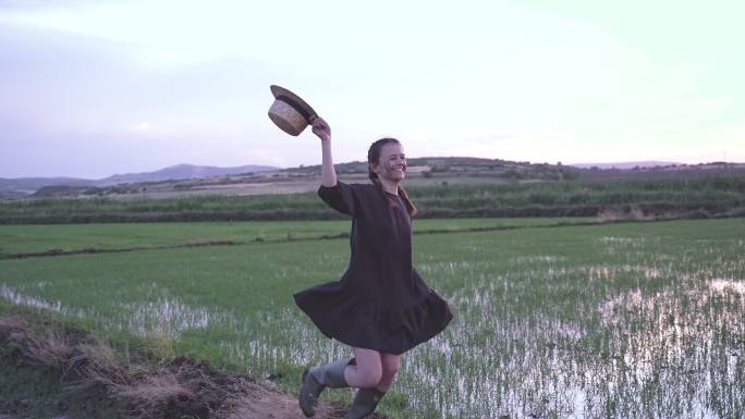 可爱的女农民，脸上戴着米杯，工作结束后微笑着在稻田上跳跃