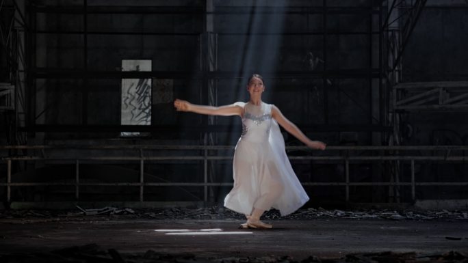 年轻女子美丽的芭蕾舞演员在黑暗中随着烟雾在灯光下跳舞。