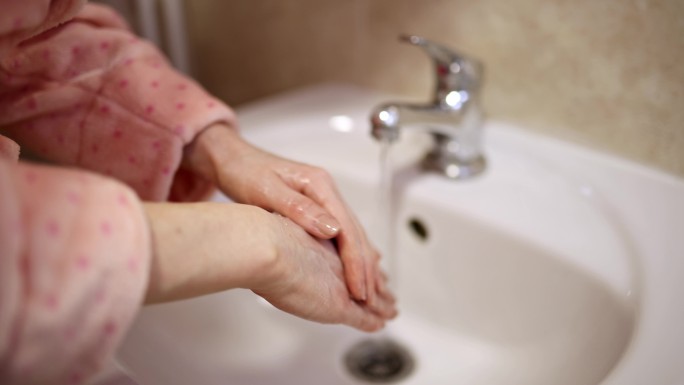 一个女人在卫生间的白色干净的洗手盆里洗手
