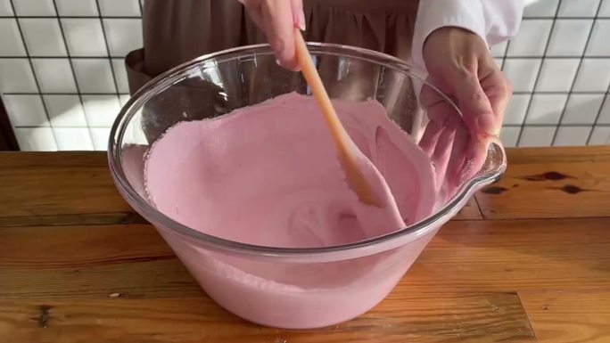 女人用抹刀在玻璃碗里搅拌奶油