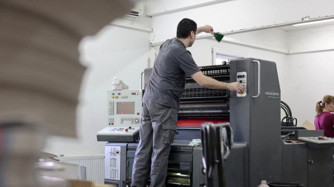 印刷厂工人正在调整自动印刷机