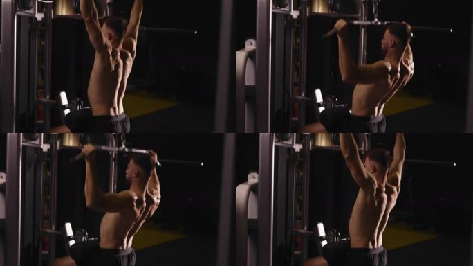 肌肉男健美运动员在健身房使用健身机锻炼