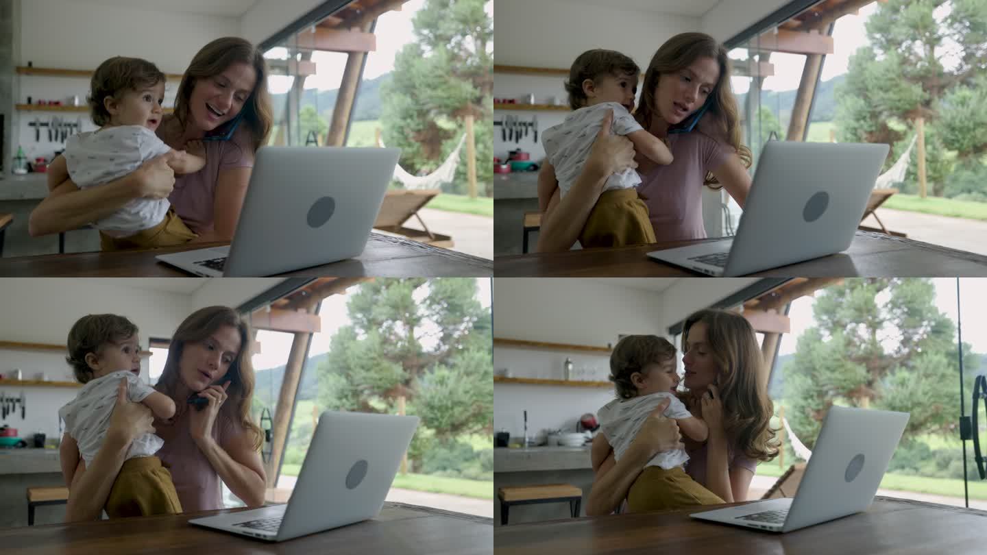 美丽的女人在家里工作，带着蹒跚学步的孩子，用笔记本电脑打电话