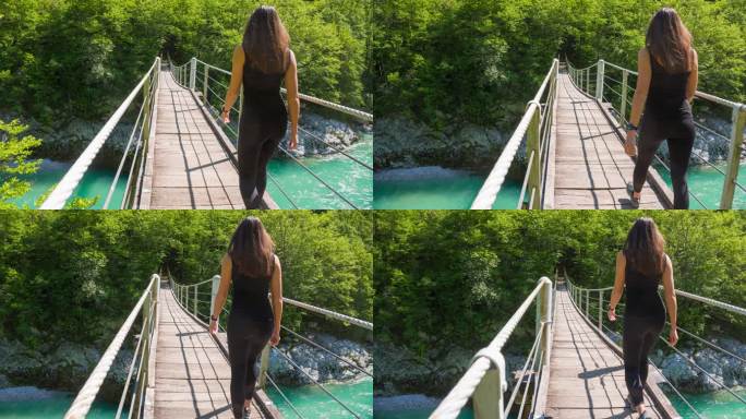 一名年轻女性在充满活力的山谷中走过一座木制吊桥