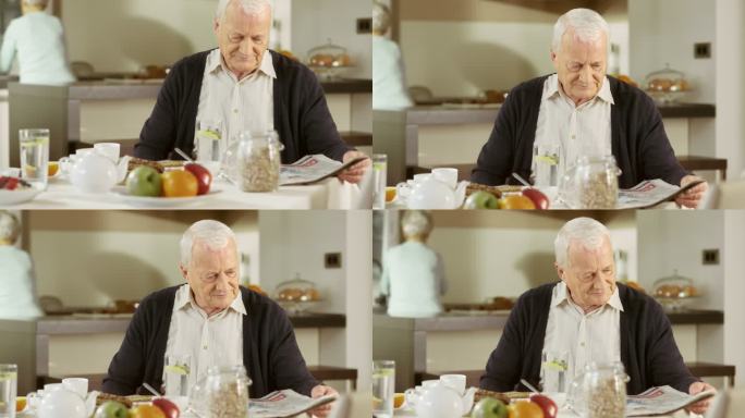 一位老人在早餐桌上看报纸