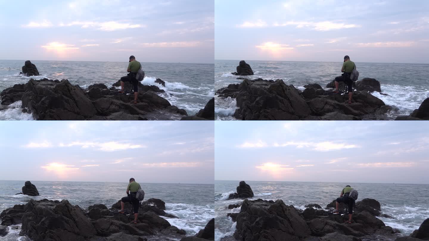 摄像师站在海边礁石上面工作