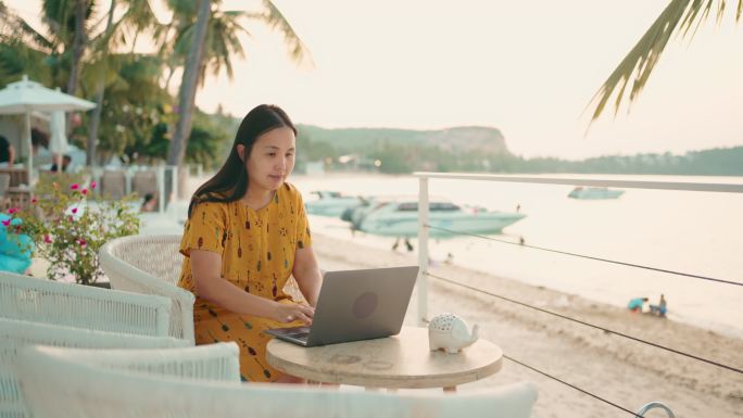 在海滩旅行时使用笔记本电脑的自由职业者。