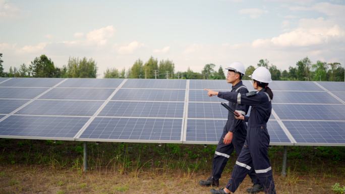 太阳能电池板发电站，电气工程师检查建筑外的太阳能电池场。