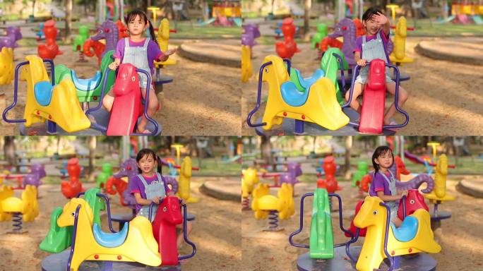 小女孩在公园的操场上骑着玩具旋转木马。
