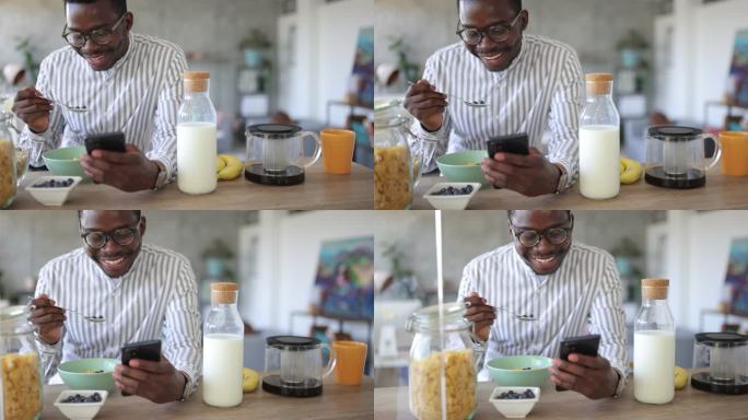 年轻人吃健康早餐，早上在家使用智能手机