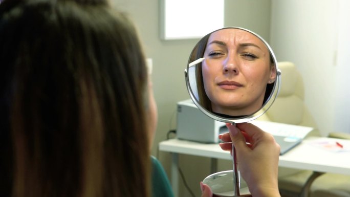 在一个医疗中心的股票视频中，一个女孩在看美容师的工作结果