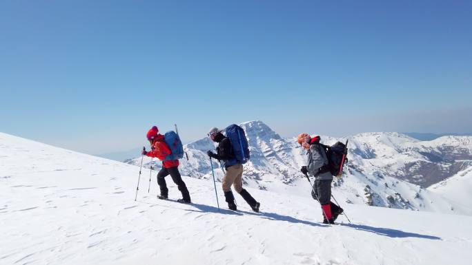 一支成功的登山队正在冬季高海拔雪山山顶的山脊上连续攀登