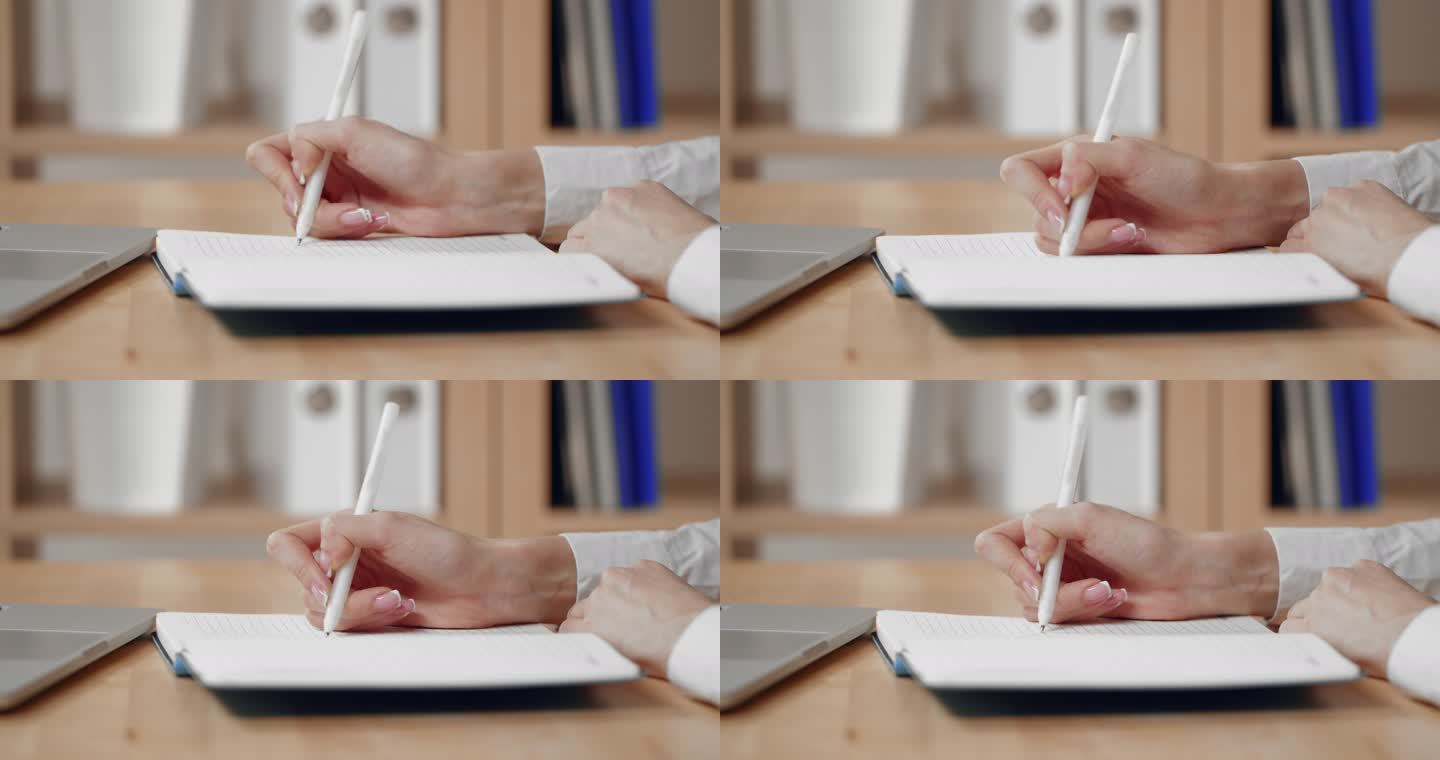一位女商人正在用笔和笔记本电脑在记事本上写字。