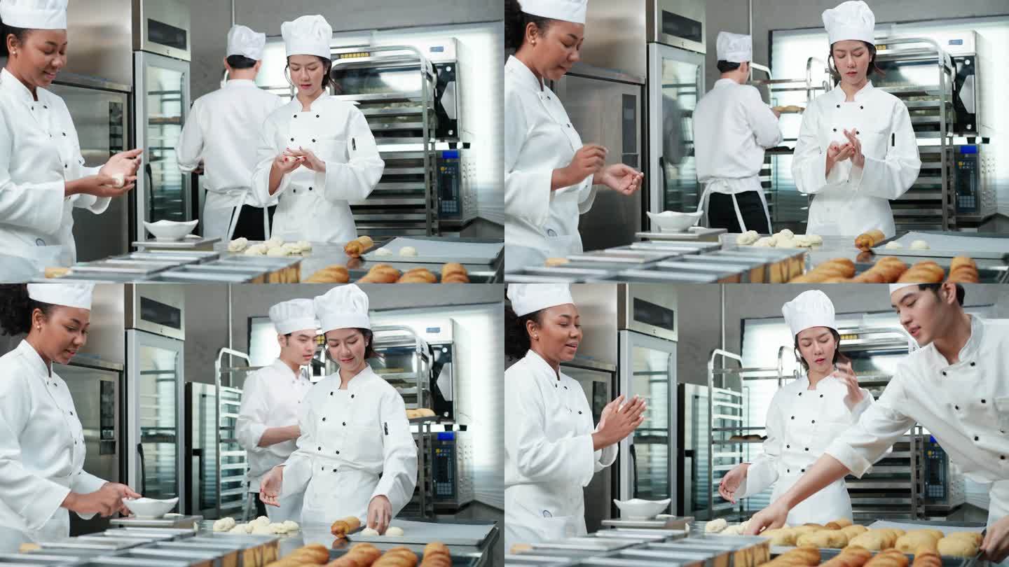 穿着白色厨师制服的亚洲和非洲年轻厨师一起工作，制作面包和面包，在烤箱中打样和烘焙之前称重、揉捏和成型