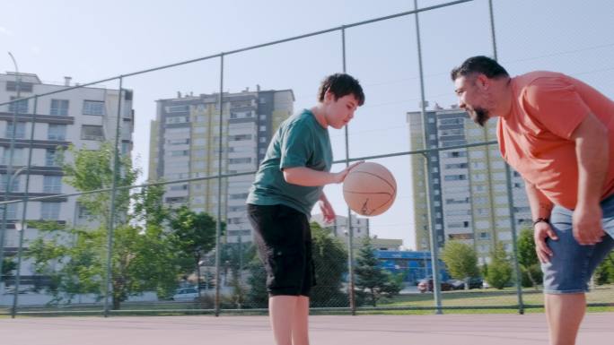 父亲和儿子在室外球场打篮球