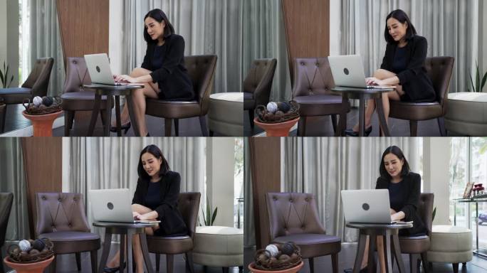 一位亚洲女商人在明亮的休息室使用笔记本电脑。