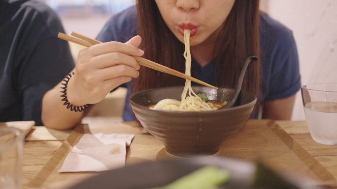 一位年轻女子正在吃拉面，一种日本面条汤。