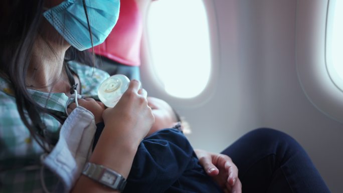 母亲坐飞机旅行时给儿子喂食。