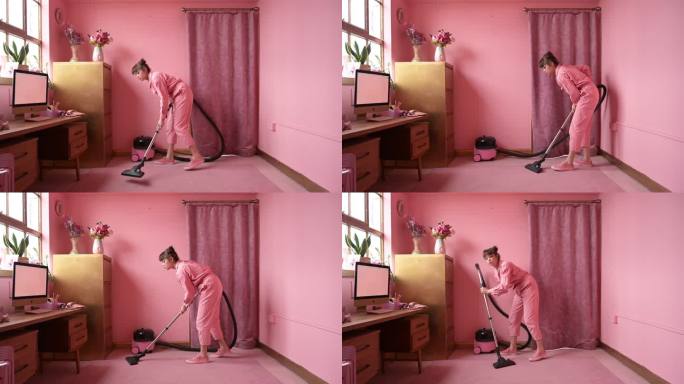 40年代初，一位女士在粉红色的家庭办公室用吸尘器清理地毯