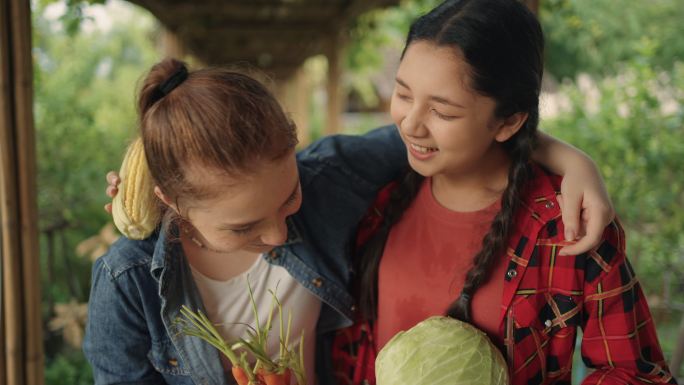 两个年轻的女农民的肖像，以他们农场的蔬菜为荣。