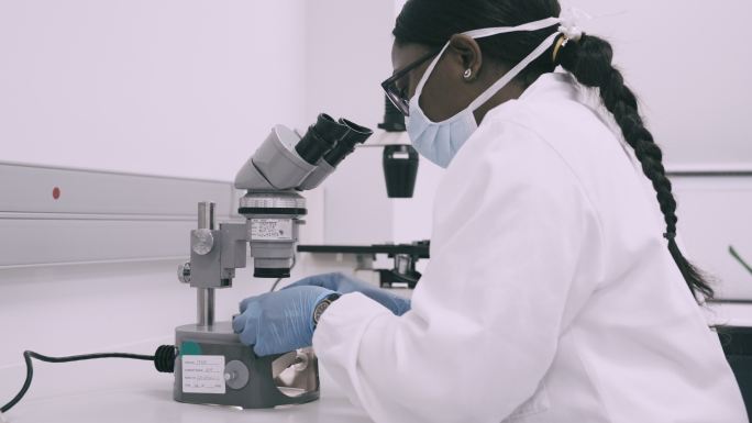 一位年轻科学家在实验室进行医学研究时使用显微镜的4k视频片段