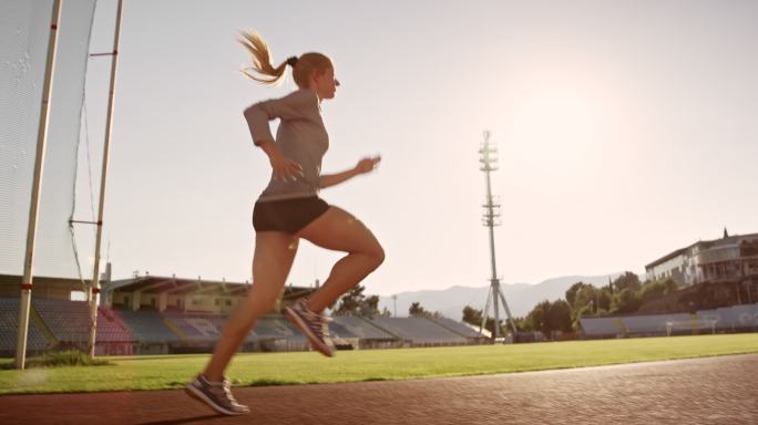 SLO MO TS女运动员在阳光体育场跑道上跑步