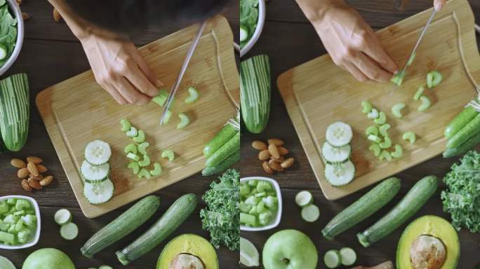 饮食概念：在平移视图的正下方，拍摄的是女人用手切蔬菜来排毒冰沙的照片。餐桌上的砧板和搅拌器