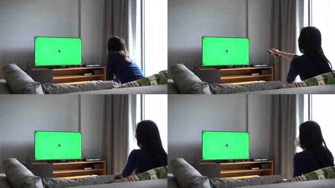 亚洲女性坐在沙发上，在家里用Chroma键看电视