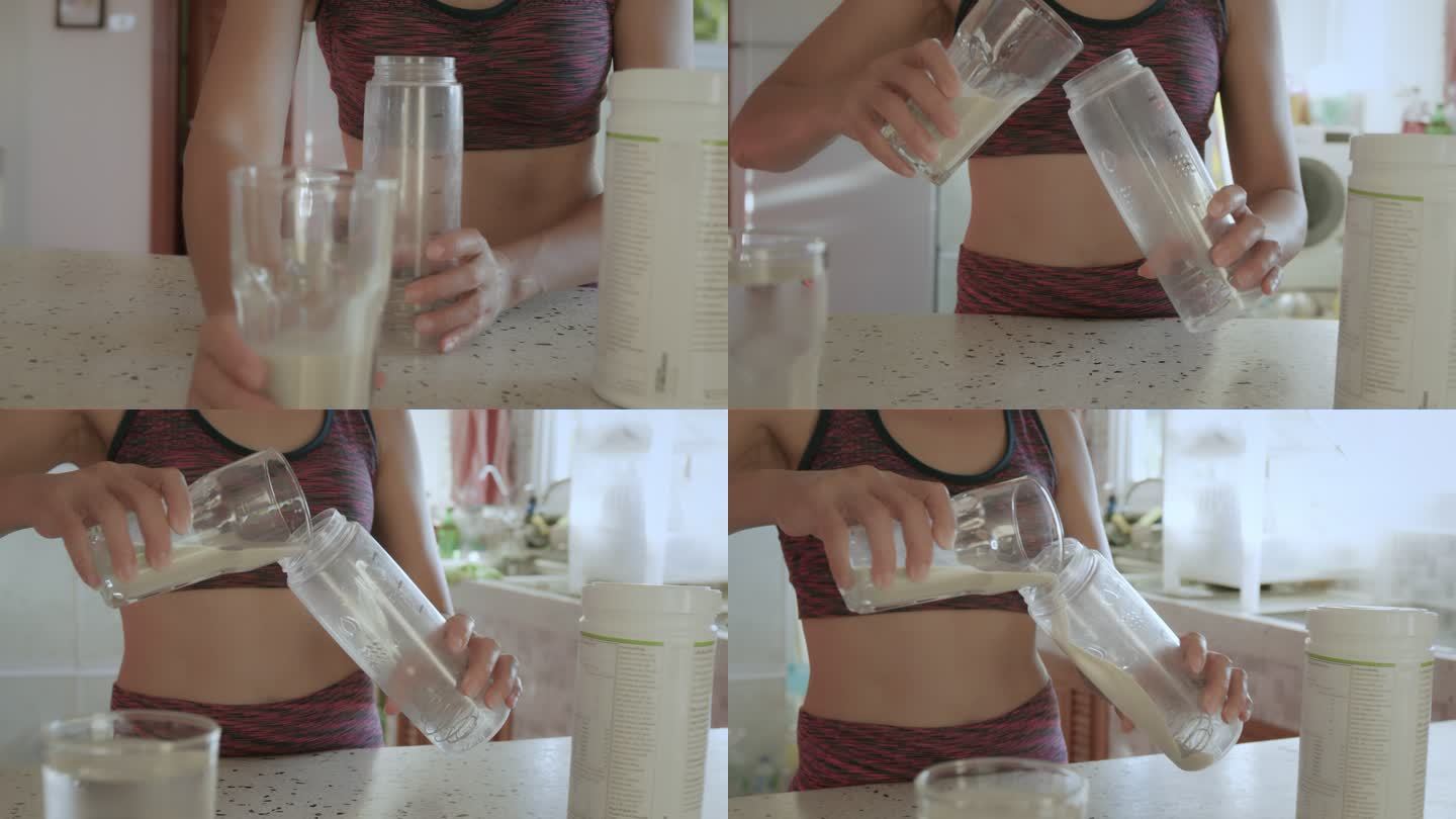 穿着运动服的亚洲年轻女性在家里的厨房里用蛋白粉制作奶昔。