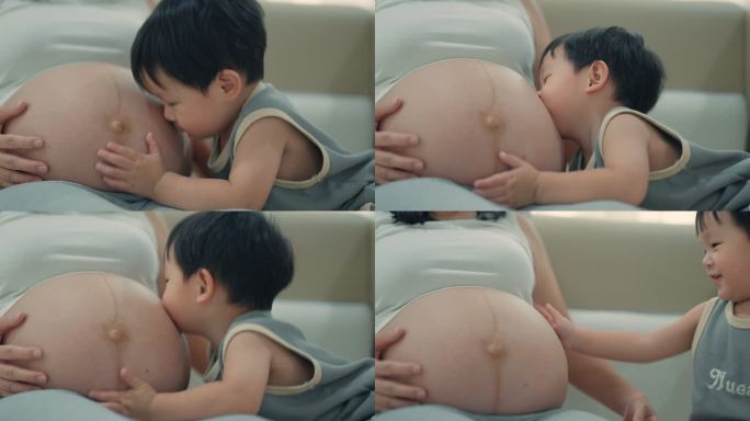 男孩在卧室里和怀孕的妈妈肚皮玩耍和接吻