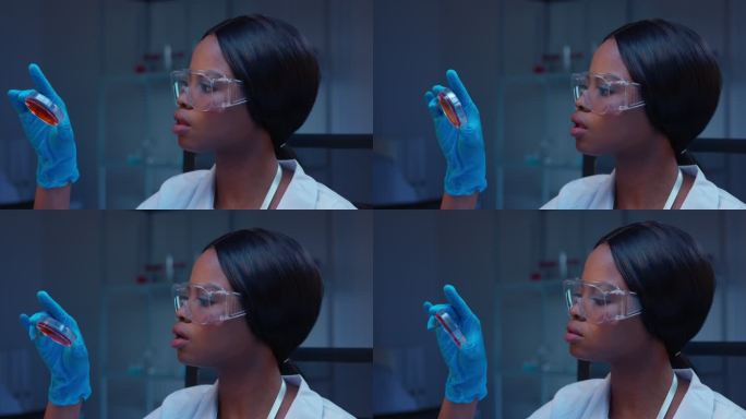 一位年轻的非洲裔美国女性微生物学家正在观察皮氏培养皿上的医学细菌检测结果