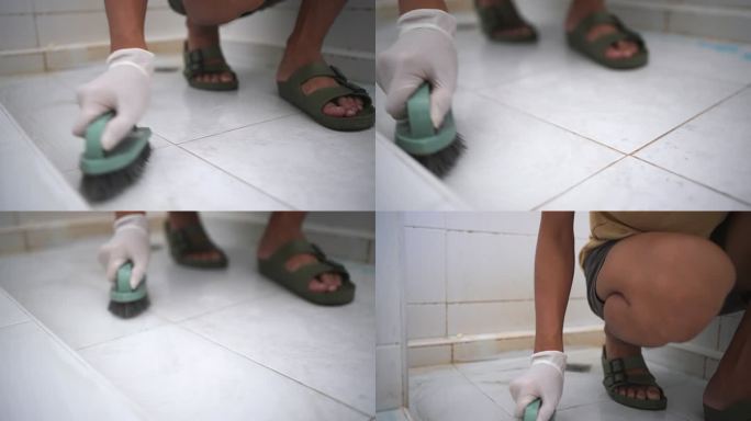 戴防护手套的男子用刷子清洁浴室