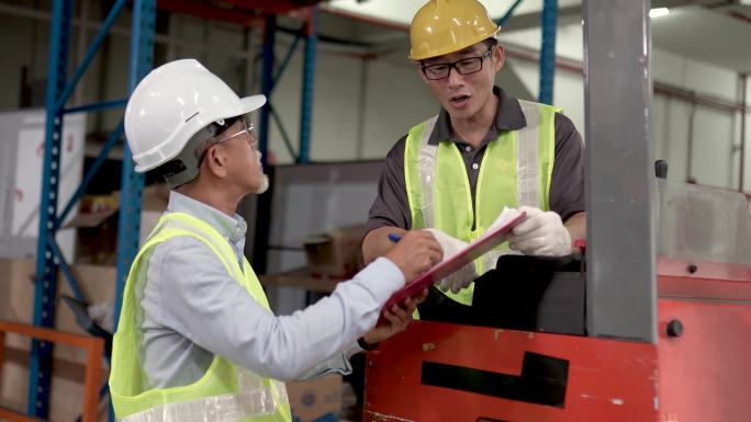 在工业工厂使用叉车完成货物移动后，亚裔中国仓库工人将文件交给主管签字
